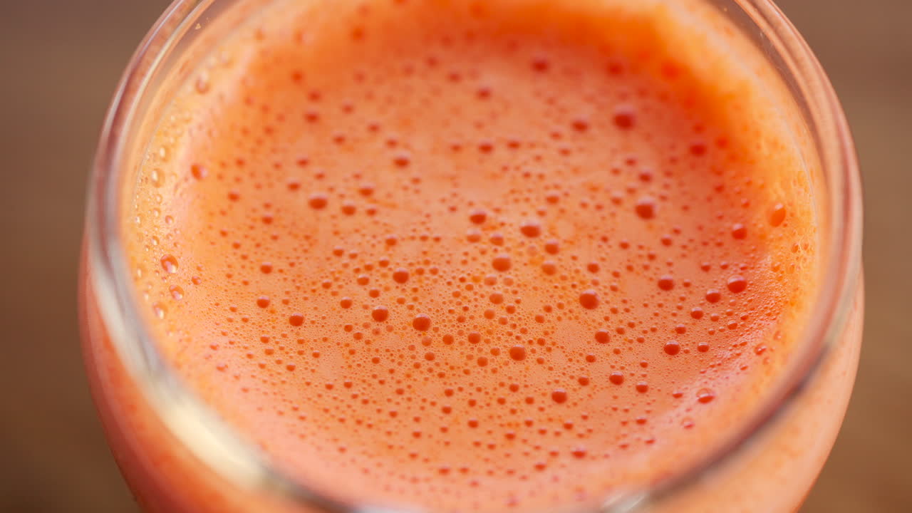 Primo piano estremo della superficie di succo d'arancia fresco con bolle e schiuma