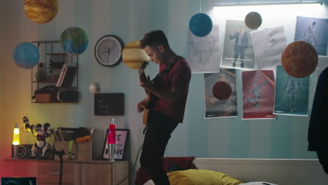 teenage boy playing electric guitar in his bedroom