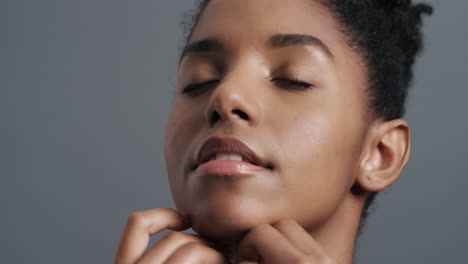 retrato en primer plano de una hermosa mujer afroamericana tocando suavemente la cara con las manos disfrutando de una piel suave y saludable, un cutis de belleza femenina natural, un concepto de cuidado de la piel