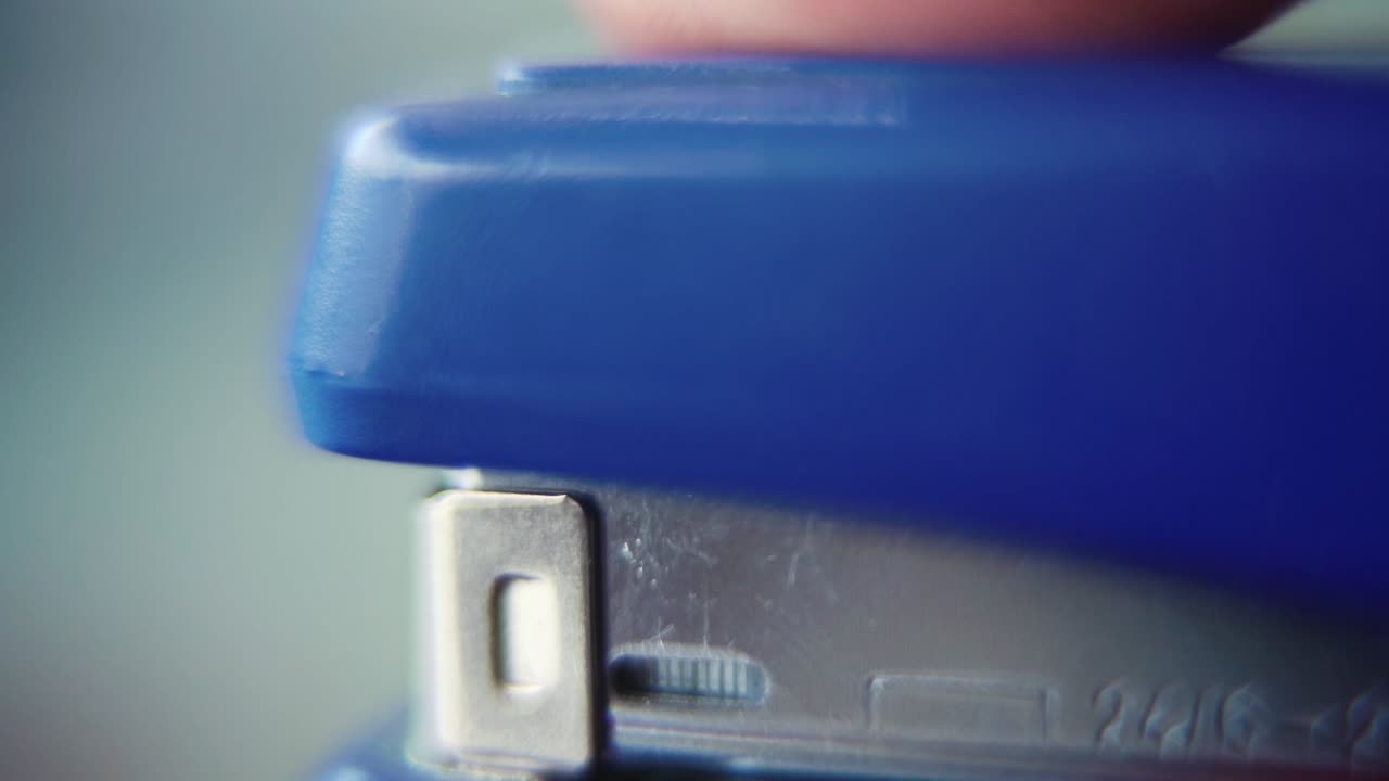 Macro close up shot, pressing on a blue stapler, super slow motion 120 fps, Full HD