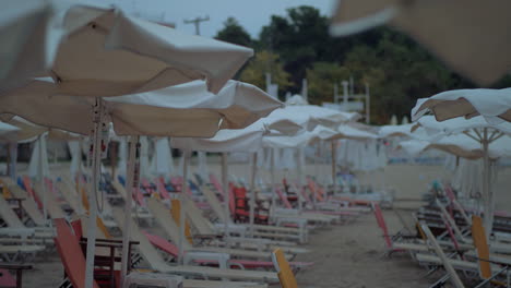sillas de sol vacías bajo sombrillas en el complejo en la noche ventosa