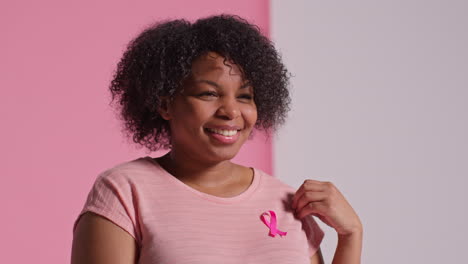 Studio-Portrait-Of-Smiling-Mid-Adult-Woman-Wearing-Pink-Breast-Cancer-Awareness-Ribbon-Against-Pink-Background-1