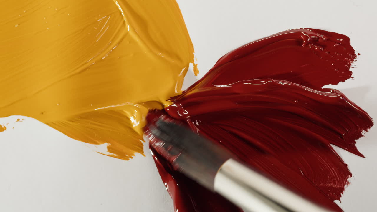 Pennello che mescola vernice rossa e gialla brillante