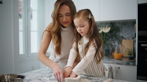 mom daughter putting dough to baking form indoors close up. girl helping parent