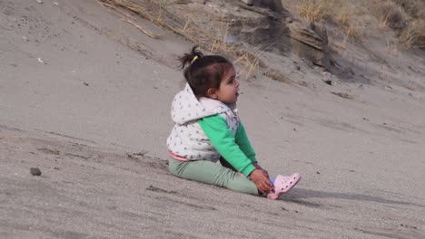 niña de dos años jugando en la arena, cámara lenta