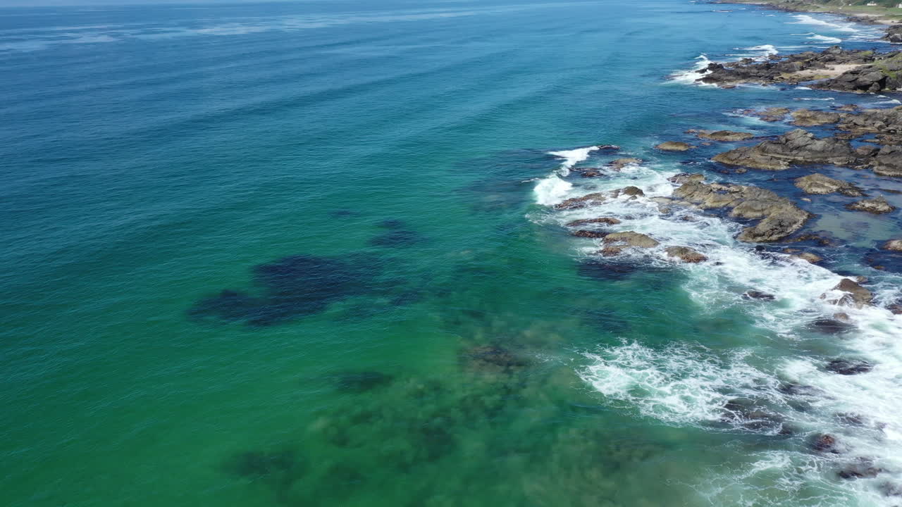 fotografía aérea mirando el mar turquesa claro chocando contra las rocas en la costa oeste de escocia