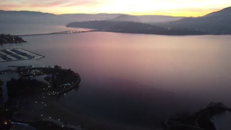 Toma-De-Drones-De-La-Ciudad-De-Kelowna-Y-Edificios-En-El-Lago-Okanogan-Con-Puesta-De-Sol