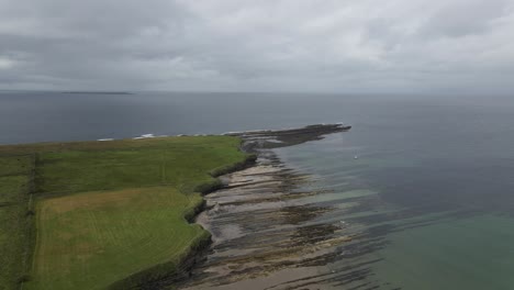 drone shot of a small headland with small cliffs in ireland