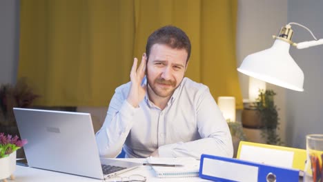 el trabajador de oficina en casa se rasca las orejas mirando a la cámara.