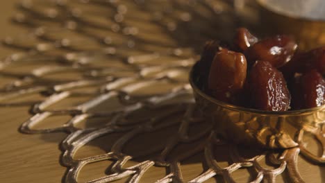 close up of hand picking up date from bowl on table in muslim home celebrating eid