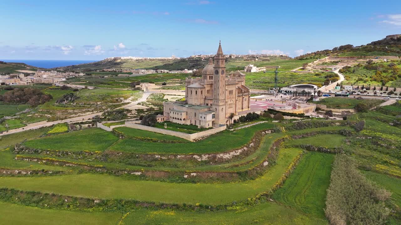 Il Santwarju Bażilika tal-Madonna ta’ Pinu a Għarb Gozo Malta si erge isolato in un paesaggio calcareo terrazzato vicino alla collina di Ta’ Għammar con una piazza del pellegrinaggio e un paesaggio rurale, orbita aerea con drone