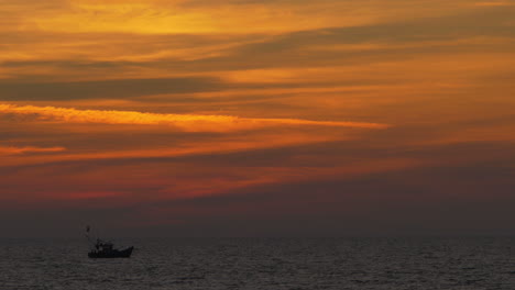 Silueta-De-Barco-Solitario-Moviéndose-De-Izquierda-A-Derecha-En-El-Océano-índico-Con-Un-Espectacular-Cielo-Colorido-Después-Del-Atardecer,-Goa,-India