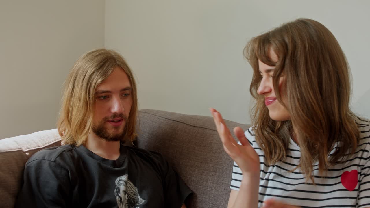 A Man and a Woman are Sitting on the Sofa, Eating Grapes - Close Up
