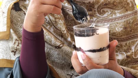 a woman holding a dessert cup with a spoon