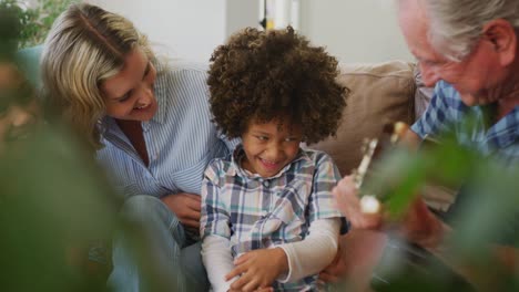 Video-of-diverse-family-siting-on-the-couch-and-grandfather-playing-the-guitar