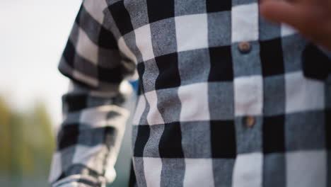 close up of man jogging in plaid shirt, hand in motion, with blurred jogger in pink behind, capturing action and movement in an outdoor setting with vibrant energy