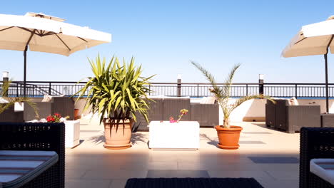 Sunny-day-and-empty-outdoor-terrace-with-couches-and-flowers