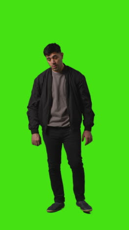 vertical video full length portrait shot of worried or stressed looking man standing against green screen 3