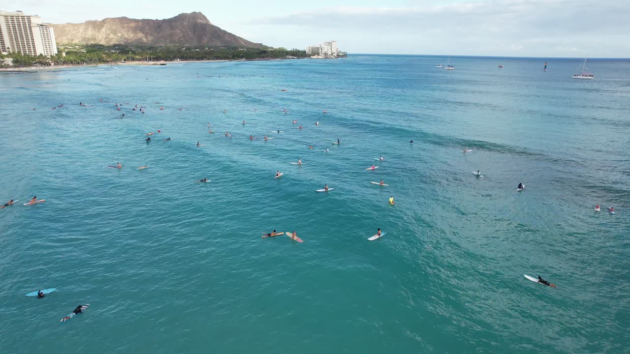Un gruppo di surfisti aspetta di prendere le onde mentre si infrangono in una popolare località per il surf.