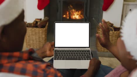 pareja afroamericana en sombreros de santa haciendo llamada de video de navidad portátil, con espacio de copia en la pantalla