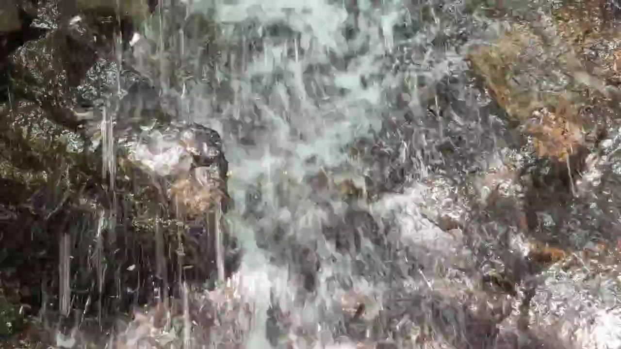 Close-up of Water Cascading Over Mossy Rocks in a Forest