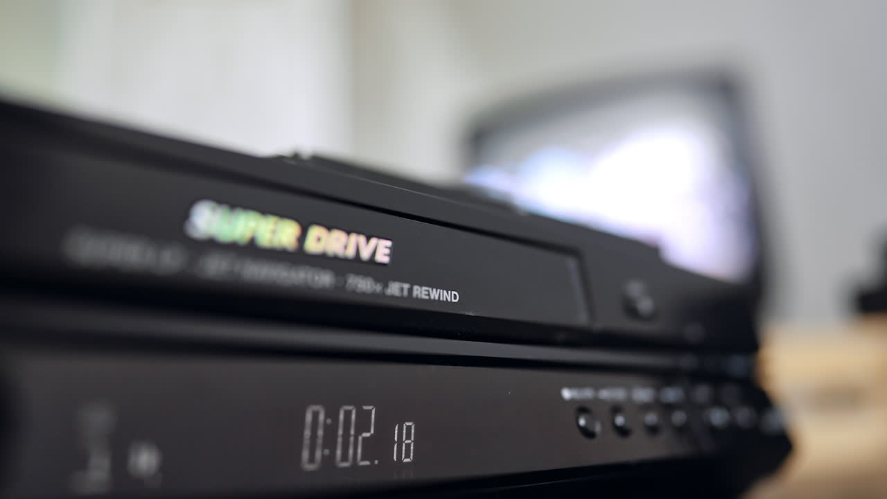 Front panel of the old VHS player. Close up. Hand presses the button on the recorder. Blurred backdrop