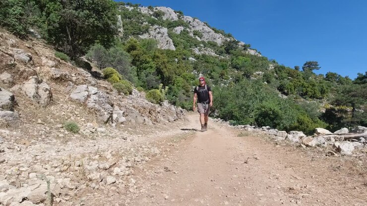 Man with backpack hiking on rocky mountain on dirt road on Lycian Way, Turkey