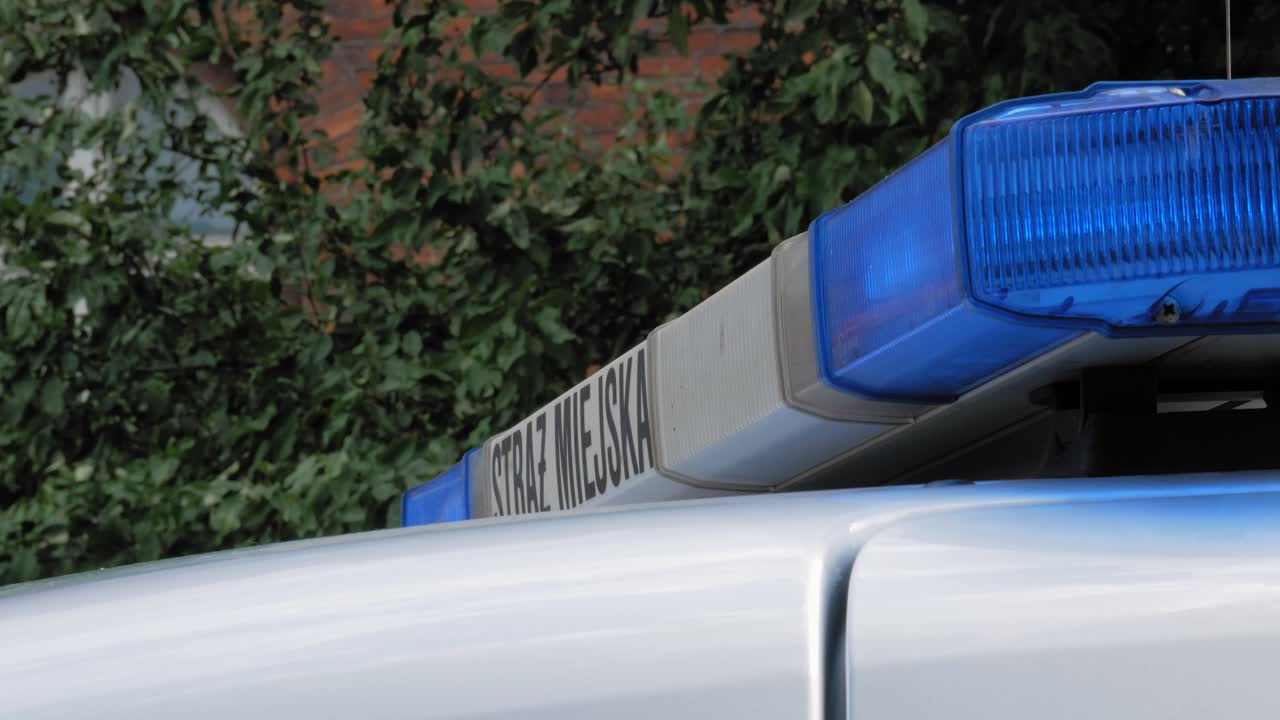 Nahaufnahme einer Lichtleiste auf dem Dach eines Polizeiautos mit blinkenden Blaulichtern tagsüber