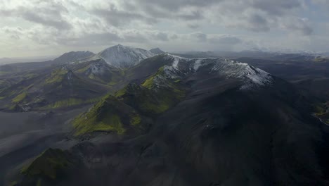 Ein-Drohnenvideo-Aus-Dem-Südisländischen-Hochland,-Das-Schwarzen-Sand,-Grünes-Moos-Und-Schnee-In-Den-Bergen-Zeigt