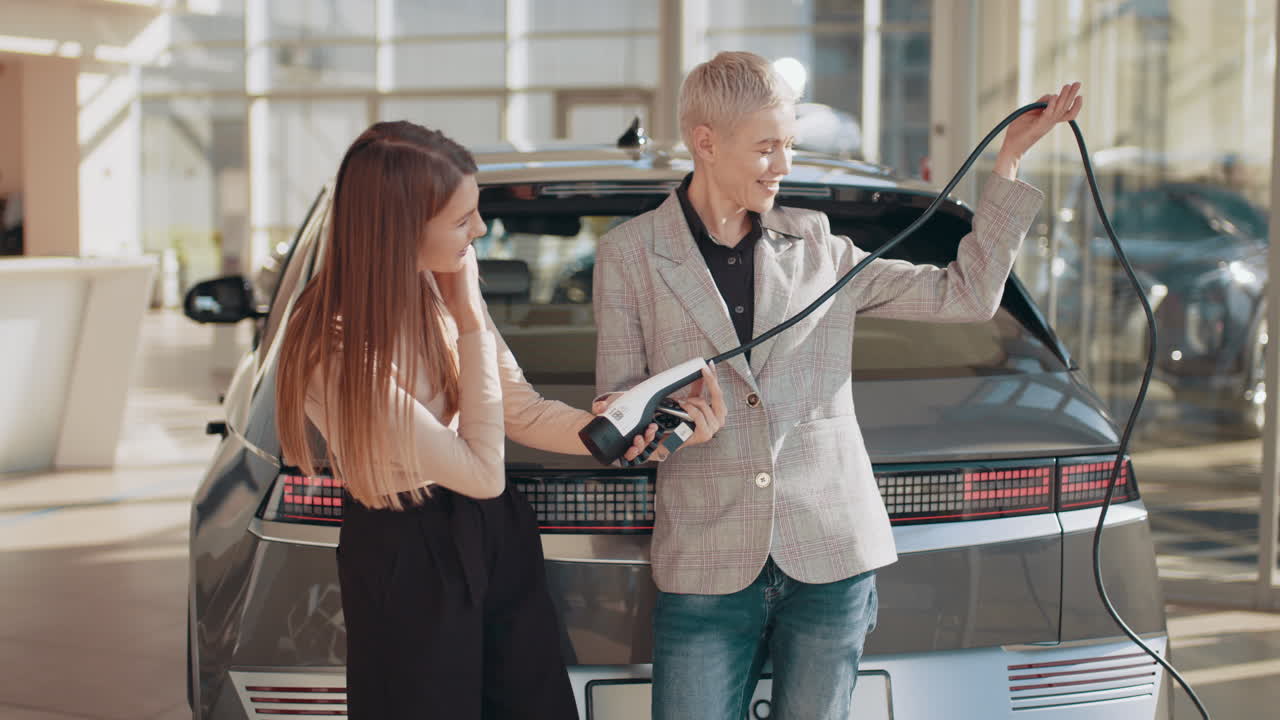 mujeres examinando la carga de automóviles eléctricos