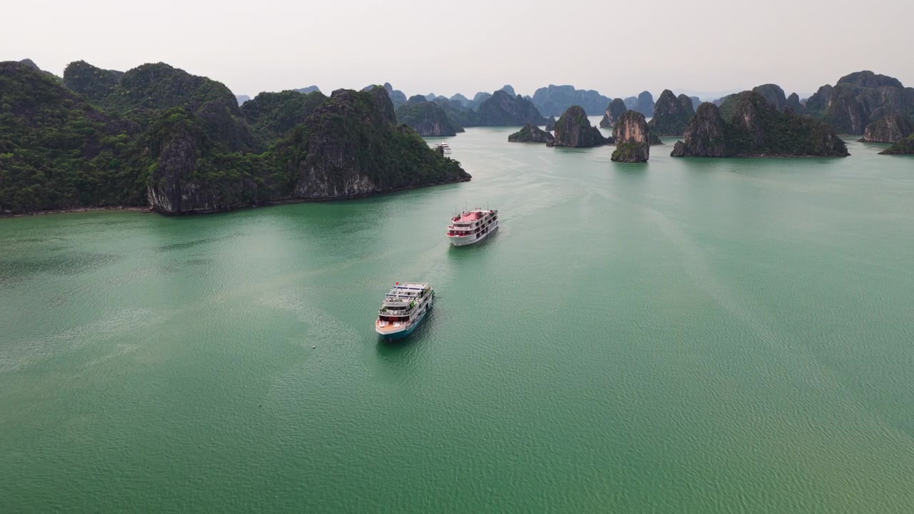 Luchtopname met Dolly In van cruiseschepen die door kalkstenen karst-eilanden navigeren in Ha Long Bay, Vietnam.