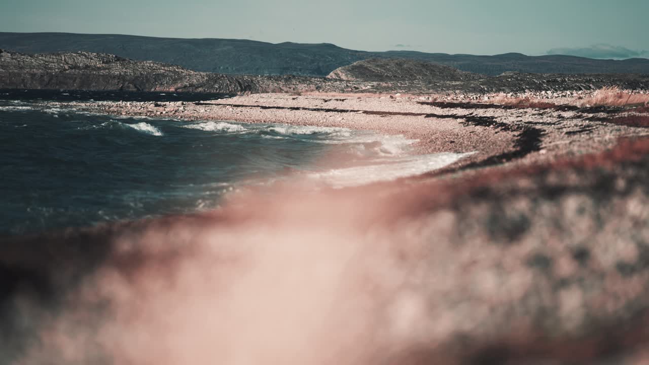 Onde forti colpiscono la spiaggia di ghiaia a Bjornnesbukta, schiumando e schizzando sulle pietre.
