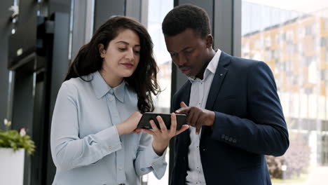 two business colleagues using smartphone in office hall
