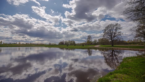 white clouds float by over a lake in a green setting