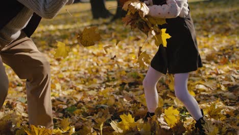 Caucasian-grandfather-playing-by-leaf-with-his-granddaughter-in-park