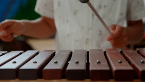 mid section of asian schoolboy playing xylophone in a classroom at school 4k