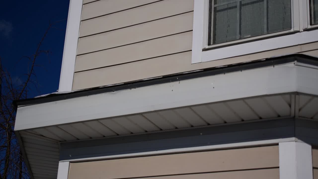 Winter snow and ice melting, dripping off edge of house roof, hydrology snowmelt