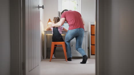 Blick-Durch-Die-Schlafzimmertür,-Während-Vater-Seiner-Tochter-Hilft,-Laptop-Auf-Dem-Schreibtisch-Zu-Benutzen