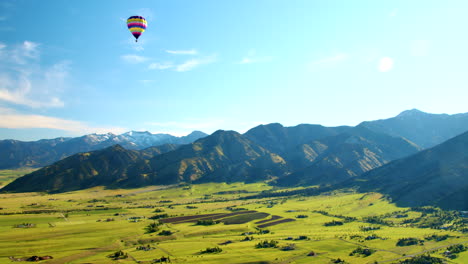 mountains with hot air balloon flying at sunrise - wide aerial view