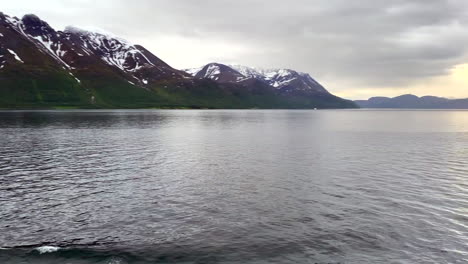 North-Cape-Norway-Honningsvåg-midnight-sun-above-the-Arctic-Circle-in-Summer,-heading-north-through-fjords-on-ocean-inlet-from-cruise-ship-1080p