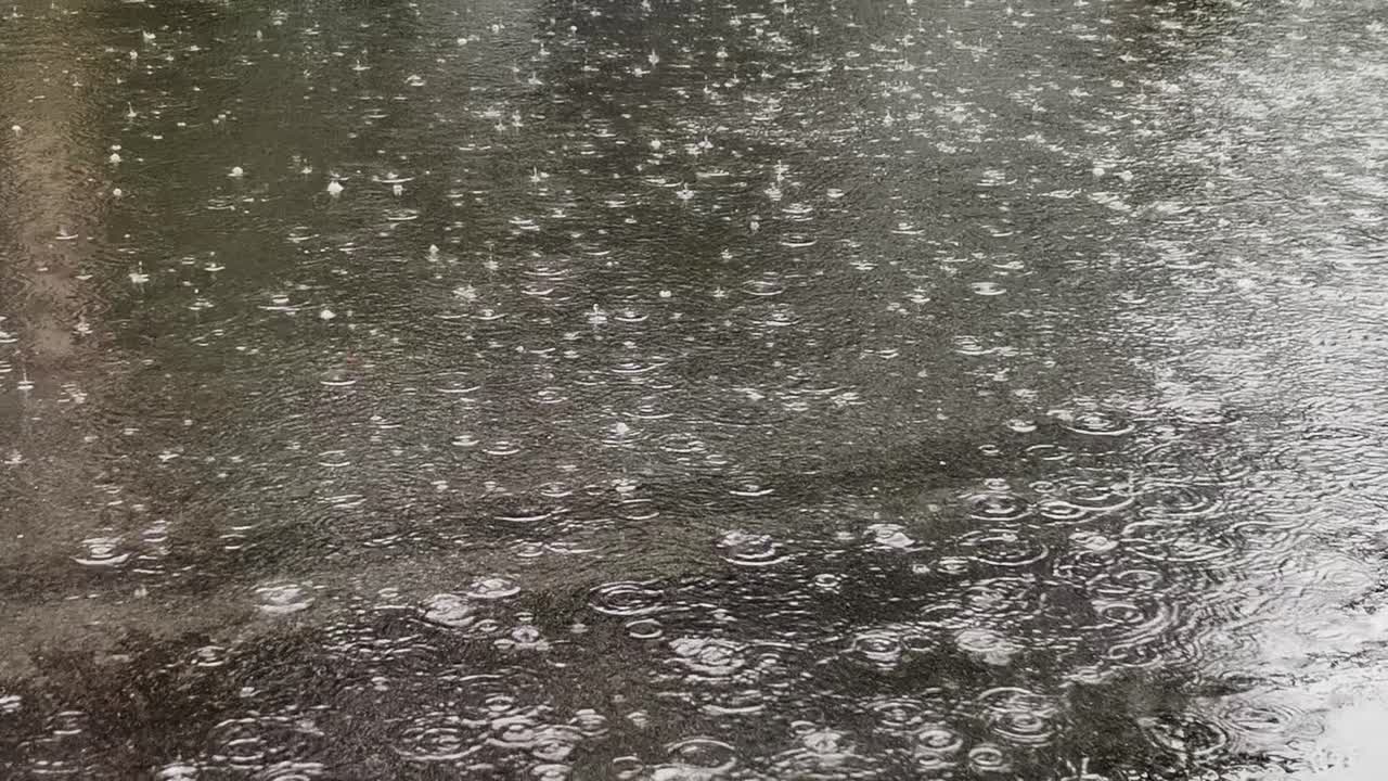 Close-Up View Captures the Intricate Patterns and Ripples Formed by Falling Raindrops on the Road