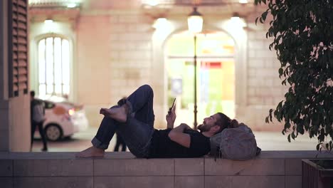 man relaxing on a city street at night