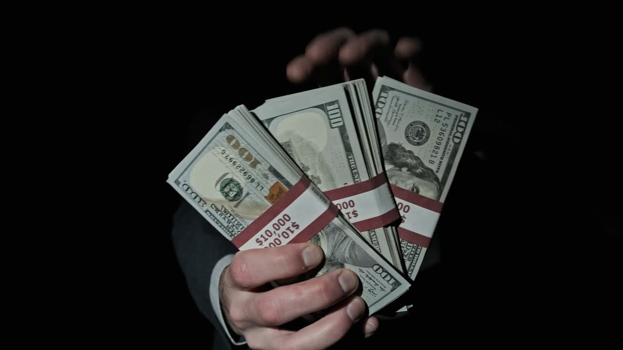 tres pilas de 10000 dólares estadounidenses paquetes en manos masculinas en fondo negro