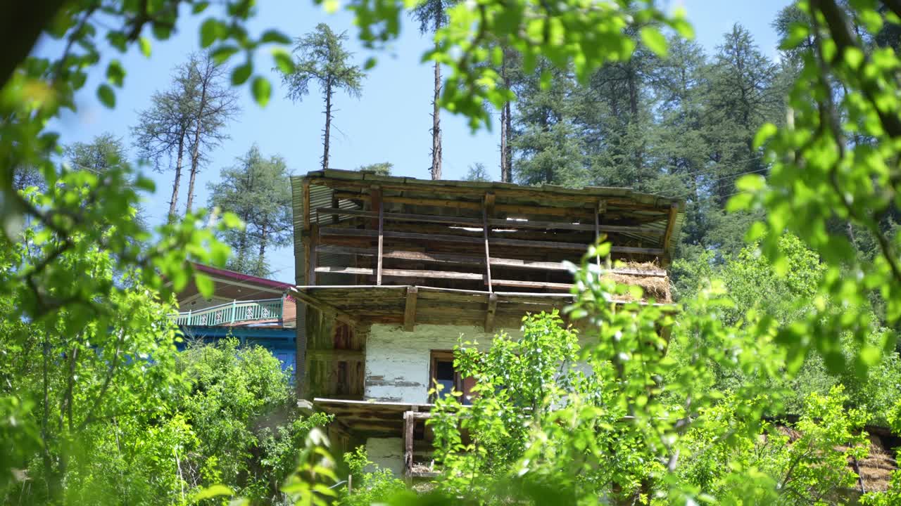 A two-story wooden house in the middle of a forest on a mountain.