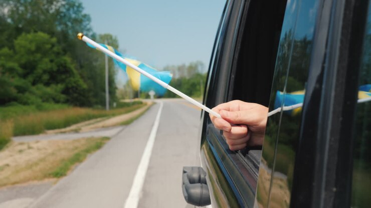 Mano con bandiera della Svezia dal finestrino di un'auto. Concetto di viaggio in Scandinavia.