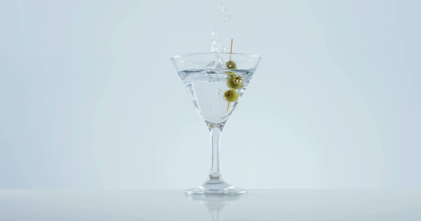 Bastoncino d'oliva che cade nel bicchiere da cocktail
