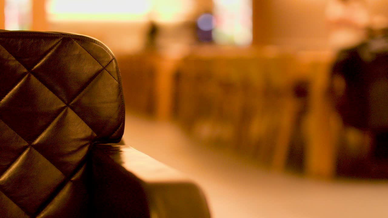 Man in casual attire walks past leather couch in warmly lit modern airport lounge