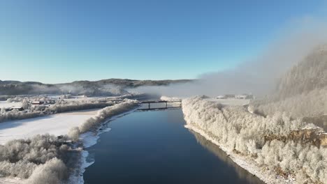 Toma-Aérea-De-Un-Paisaje-Noruego-Brumoso-Y-Soleado-En-Capas-Con-Un-Puente-De-Tren