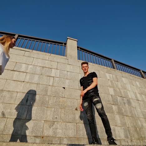 modern dancers in the street. urban lifestyle. hip-hop generation. boy's and girl's emotional moves on the video. young couple at stone wall background is looking into the camera.