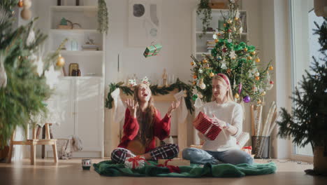 playful sisters tossing up christmas gift boxes at home